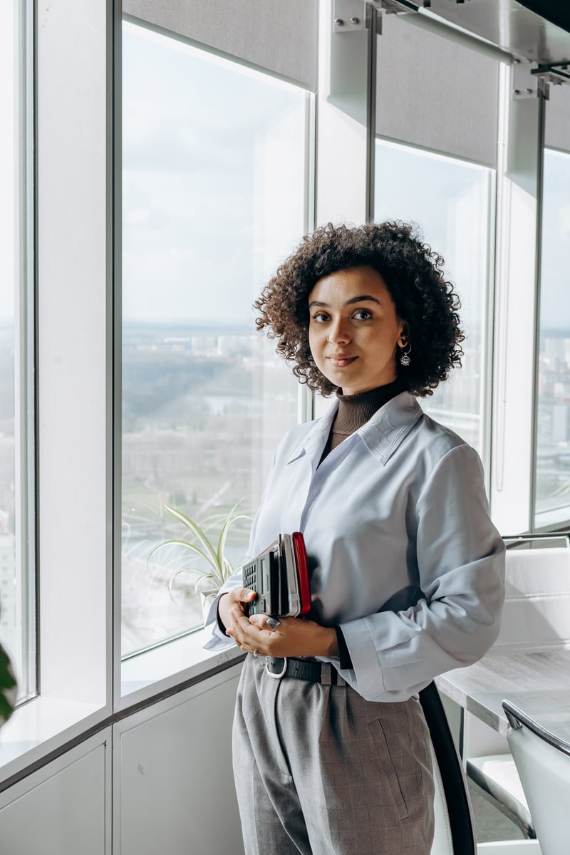 Woman in Gray Long Sleeves Shirt Standing beside Glass Window